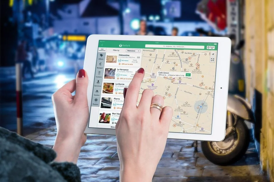 Des mains tenant une carte de crédit pendant un achat en ligne sur un ordinateur portable posé sur une table en bois.