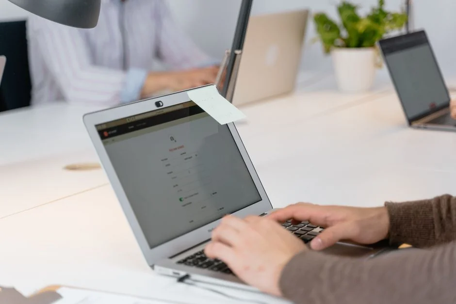 Two people shopping for shoes online using a laptop and smartphone at home.